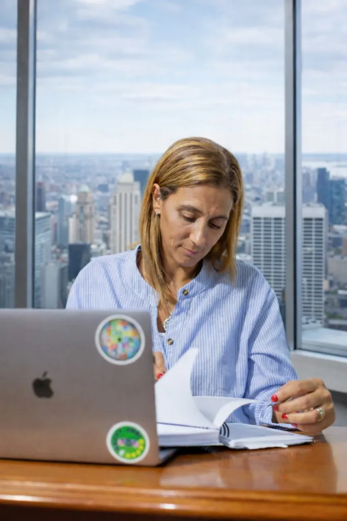 Marina Fernández en su espacio de trabajo, revisando notas frente a un ventanal con vista a la ciudad